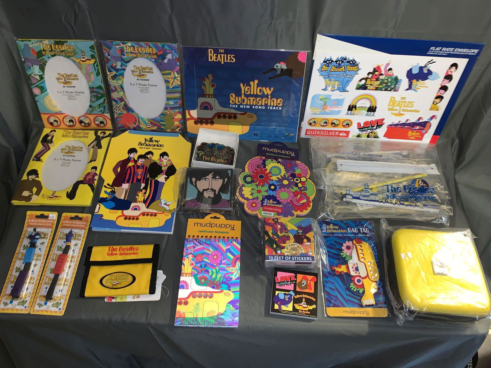 Large Grouping of Yellow Submarine Memorabilia: A large grouping of "Yellow Submarine" memorabilia including two groupings of stickers, two pencil cases with pencils, etc., CD case, bag tag, cel, belt buckle, three note pads, coaster set, fold & ma