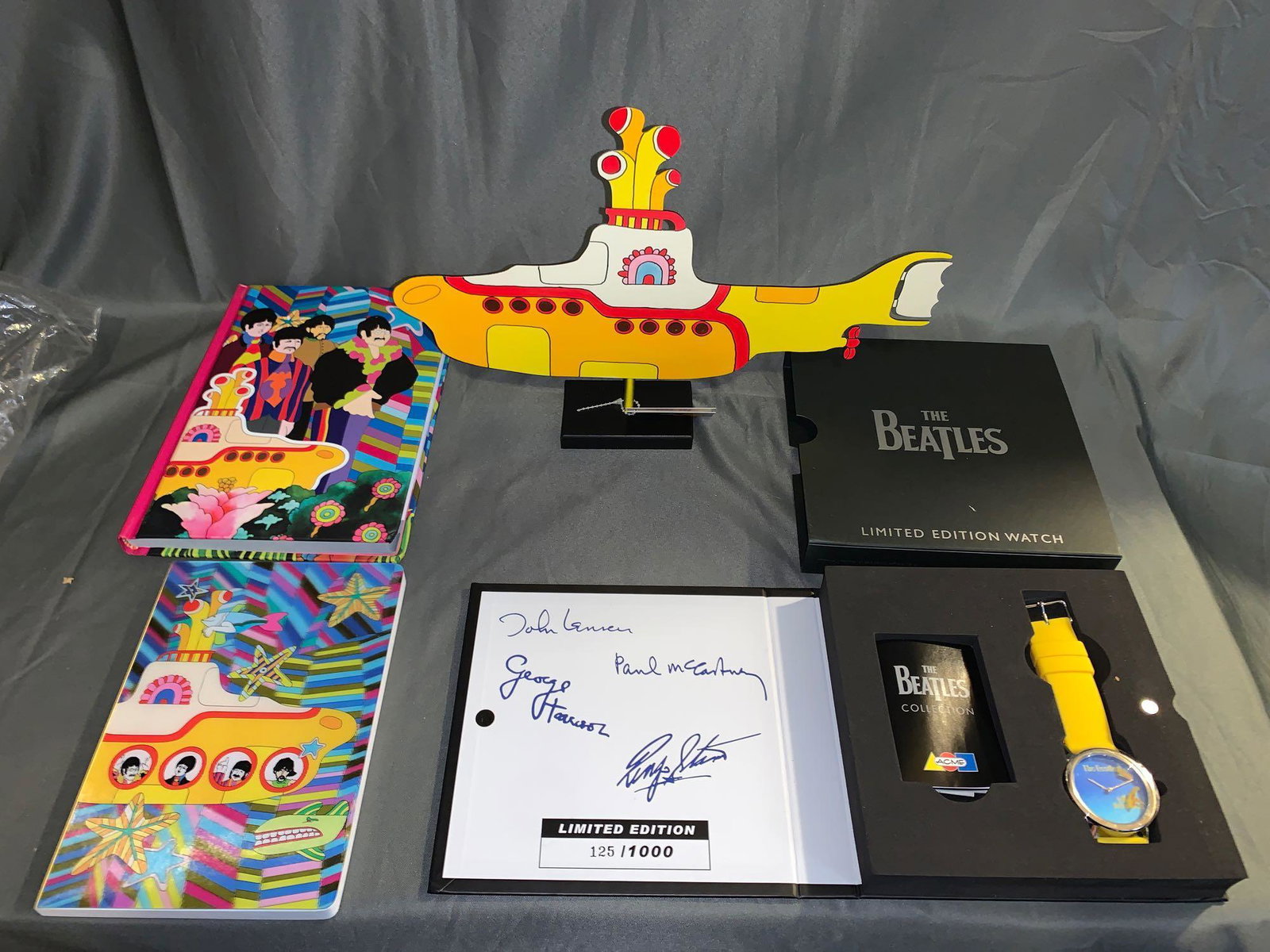 Beatles Yellow Submarine Memorabilia Grouping: A Beatles "Yellow Submarine" memorabilia grouping, including a metal sculpture by Judie Bomberger, two journals and a watch in its original packaging. Sculpture: 8in tall x 12in long.