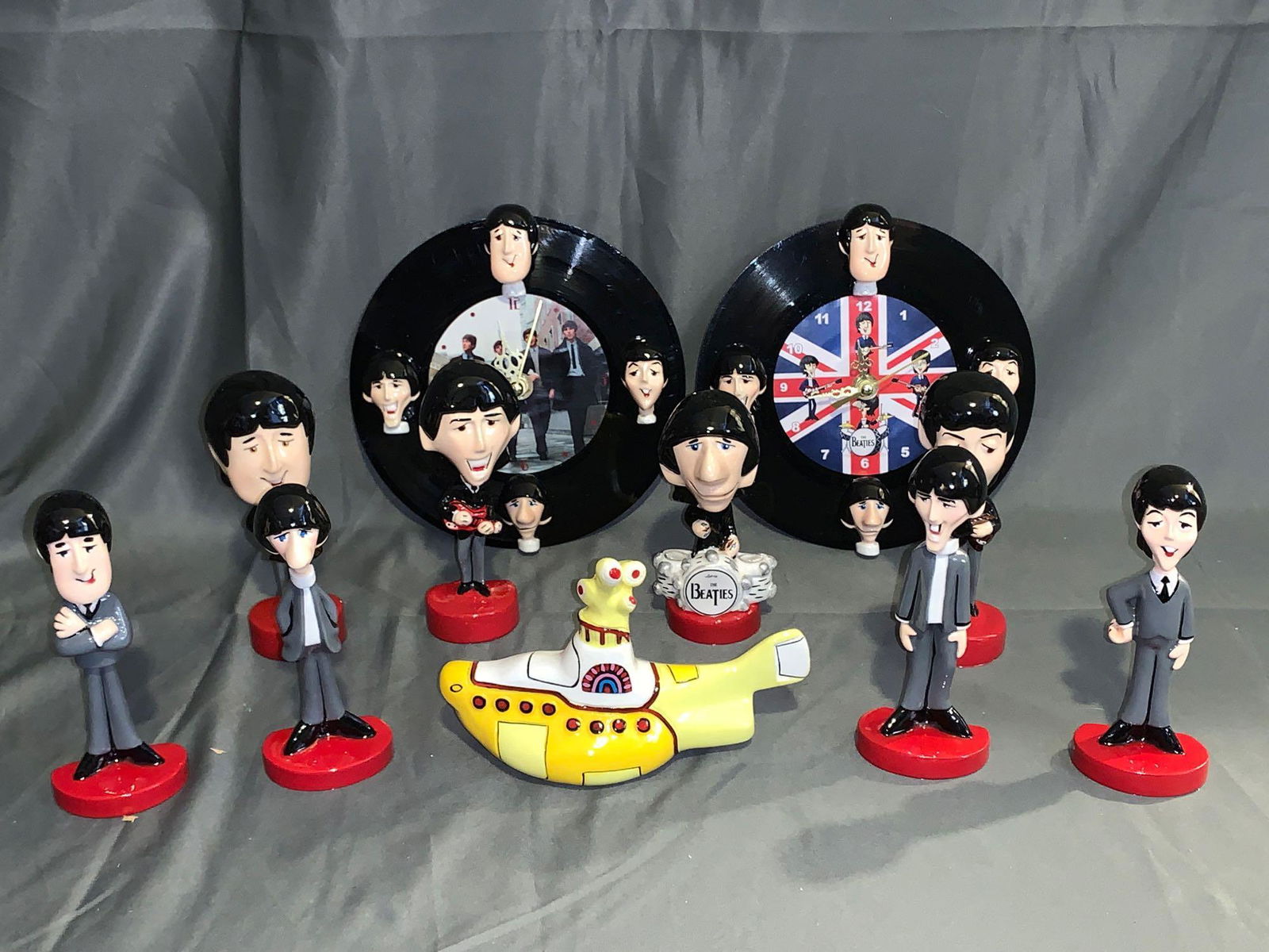 Grouping of Beatles Memorabilia from Mexico: A grouping of Beatles Memorabilia from Mexico, including a set of four cartoon figures, a set of four big head cartoon figures, a Bossuns-style Yellow Submarine and two wall clocks made from 45rpm rec