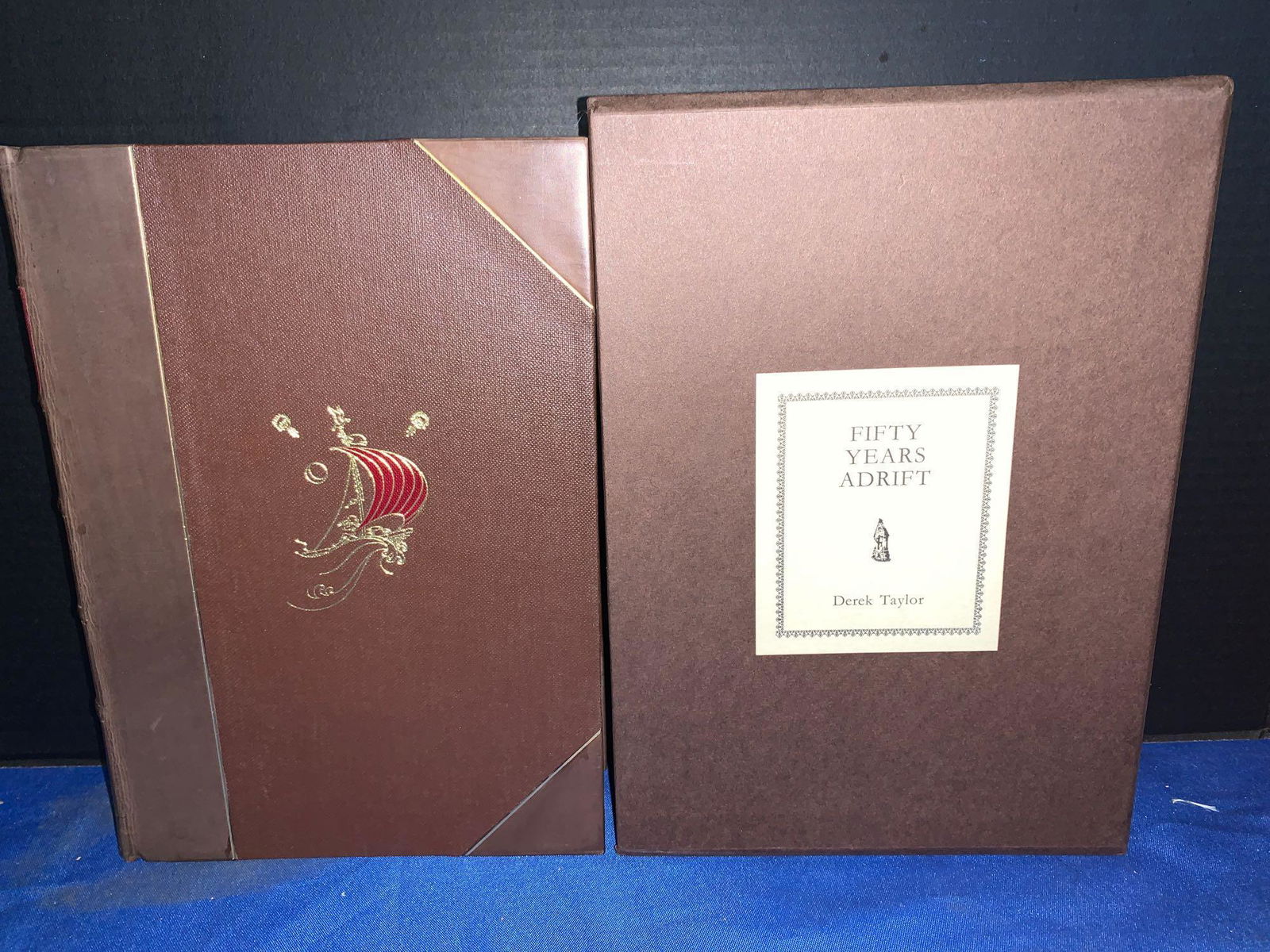 George Harrison Signed Book, Fifty Years Adrift: "Fifty Years Adrift" (1984), signed by the author Derek Taylor and by George Harrison. Produced in partial leather binding and gold edge paper with slip case, Genesis Publications marketed this book a