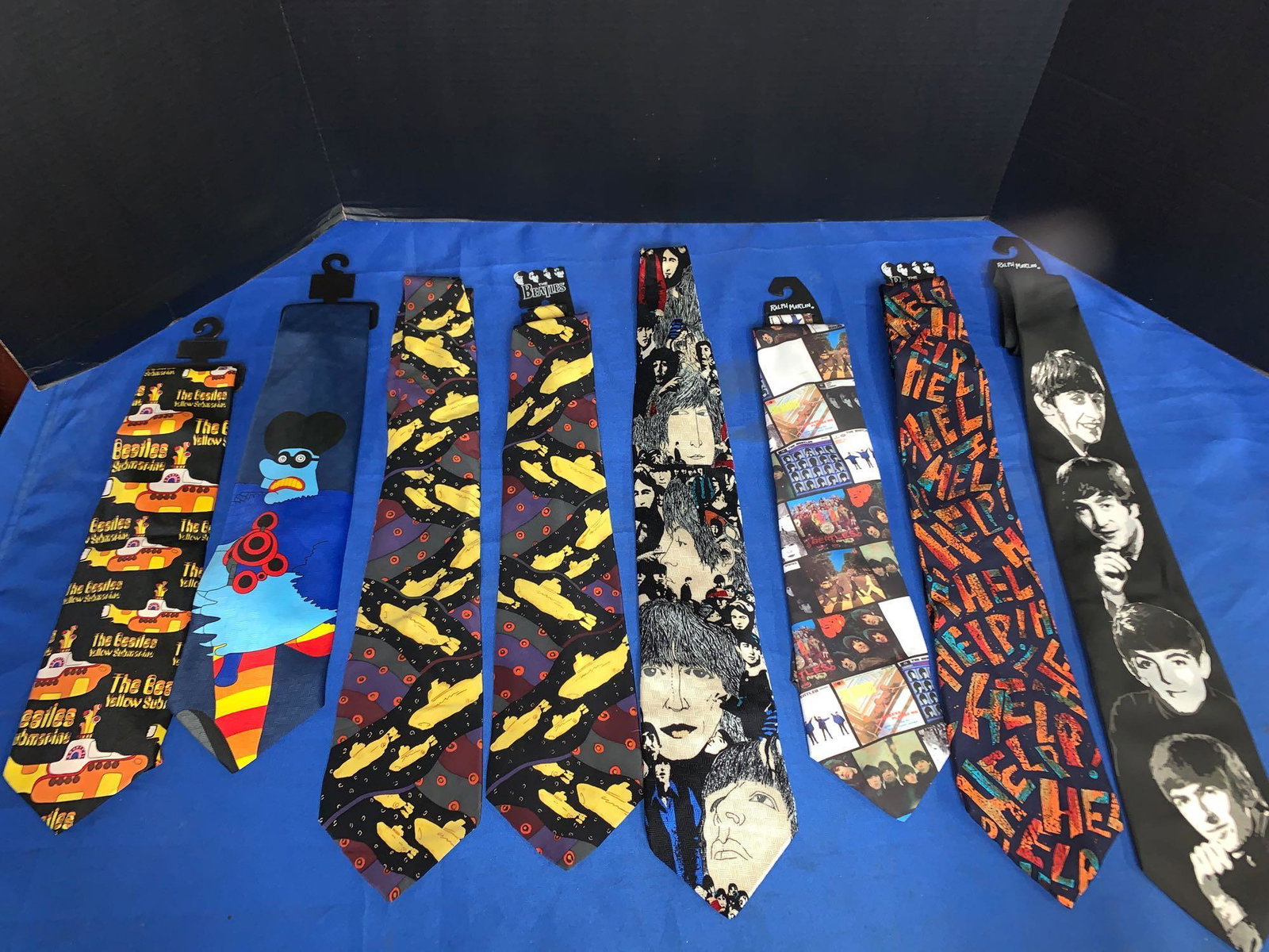 Eight Beatles Ties: A lot of eight Beatles ties including three "Yellow Submarine", one "Help", one "Revolver", one album cover tie, one with the four Beatles portraits, and a "Running Meanie" tie.