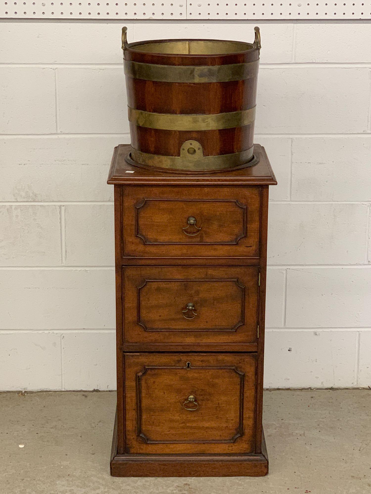 Georgian Mahogany Pedestal Cellarette: A Georgian mahogany cellarette having a brass-bound bucket cistern top over a pedestal cabinet, and featuring a drawer over a cabinet over a lined four-compartment cellarette base. 45-1/2in tall x 16-