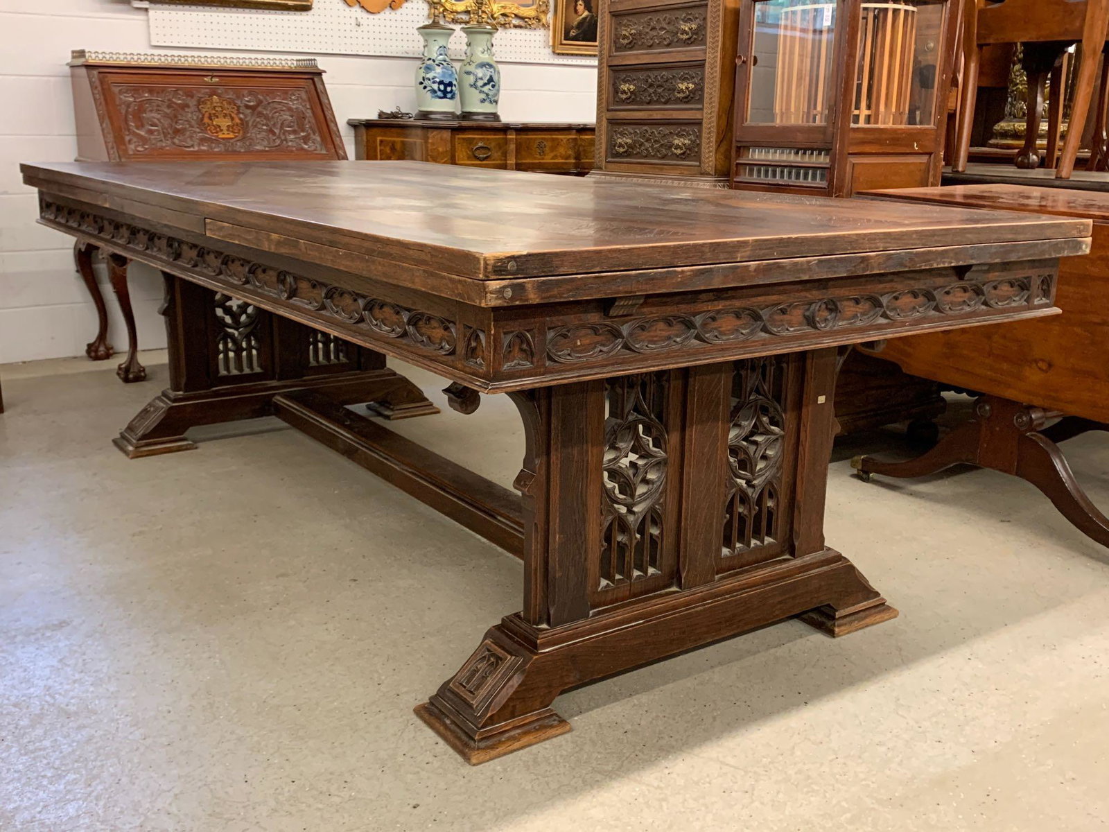 French Gothic Oak Dining Table: A French Gothic oak extension dining table having a rectangular parquetry top, two refractory leaves, carved frieze, and carved trestle base. 30-1/2in tall x 94in long x 47in wide. Each leaf: 35in.