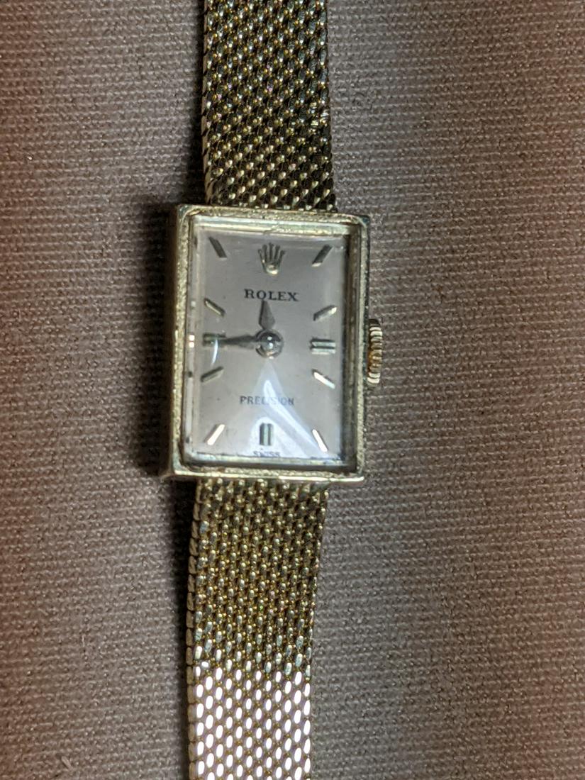 Lady's 18K Gold Rolex Wristwatch: A lady's Rolex Precision wristwatch with 18K yellow gold case and tapered band, and rectangular face. 17 jewel. Length: approx. 6.25in. 15.5dwt total.