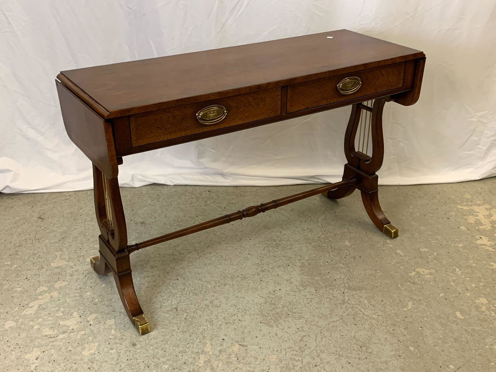 Baker Mahogany Sofa Table: A Baker mahogany drop-leaf sofa table with two drawers and lyre-form base. 28 in tall x 45 in wide x 16 in deep.