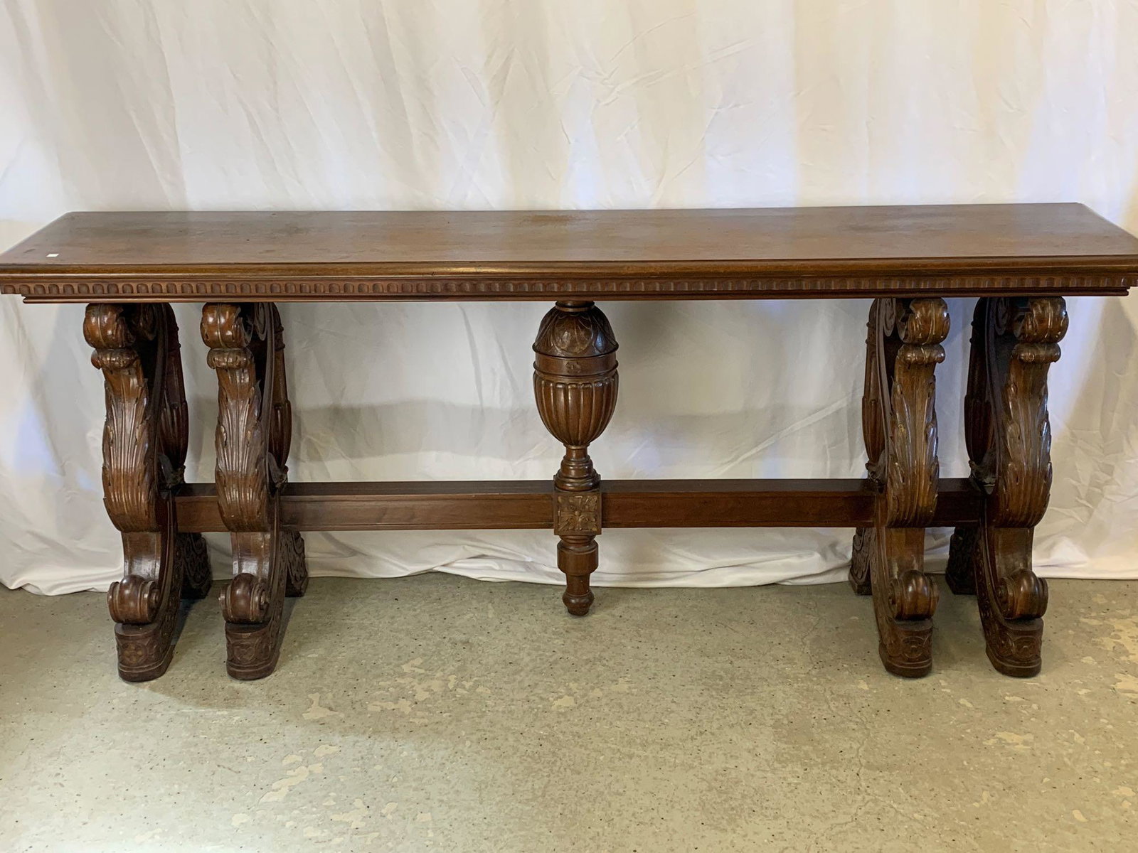 Substantial Victorian Carved Console Table: A substantial Victorian carved walnut console table with rectangular top over a base with scrolling acanthus carved legs and central urn support on a rectangular stretcher. 33-1/2 in tall x 84 in wide