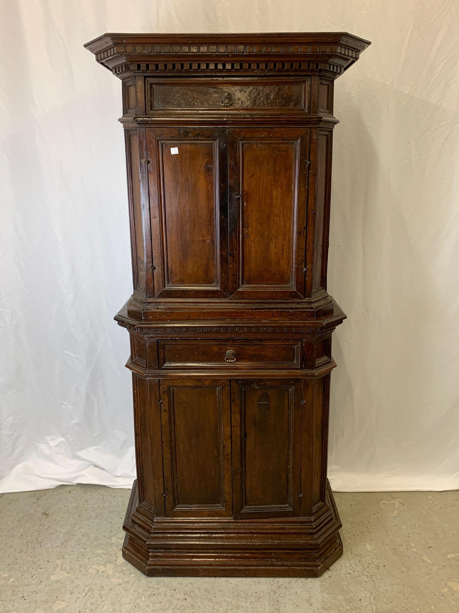 Italian Renaissance Walnut Cabinet: A 16th/17th Century Italian Renaissance walnut cabinet in two parts having a flat molded and dental key edged top over a single drawer and two doors, over a cabinet with the same configuration, in a m