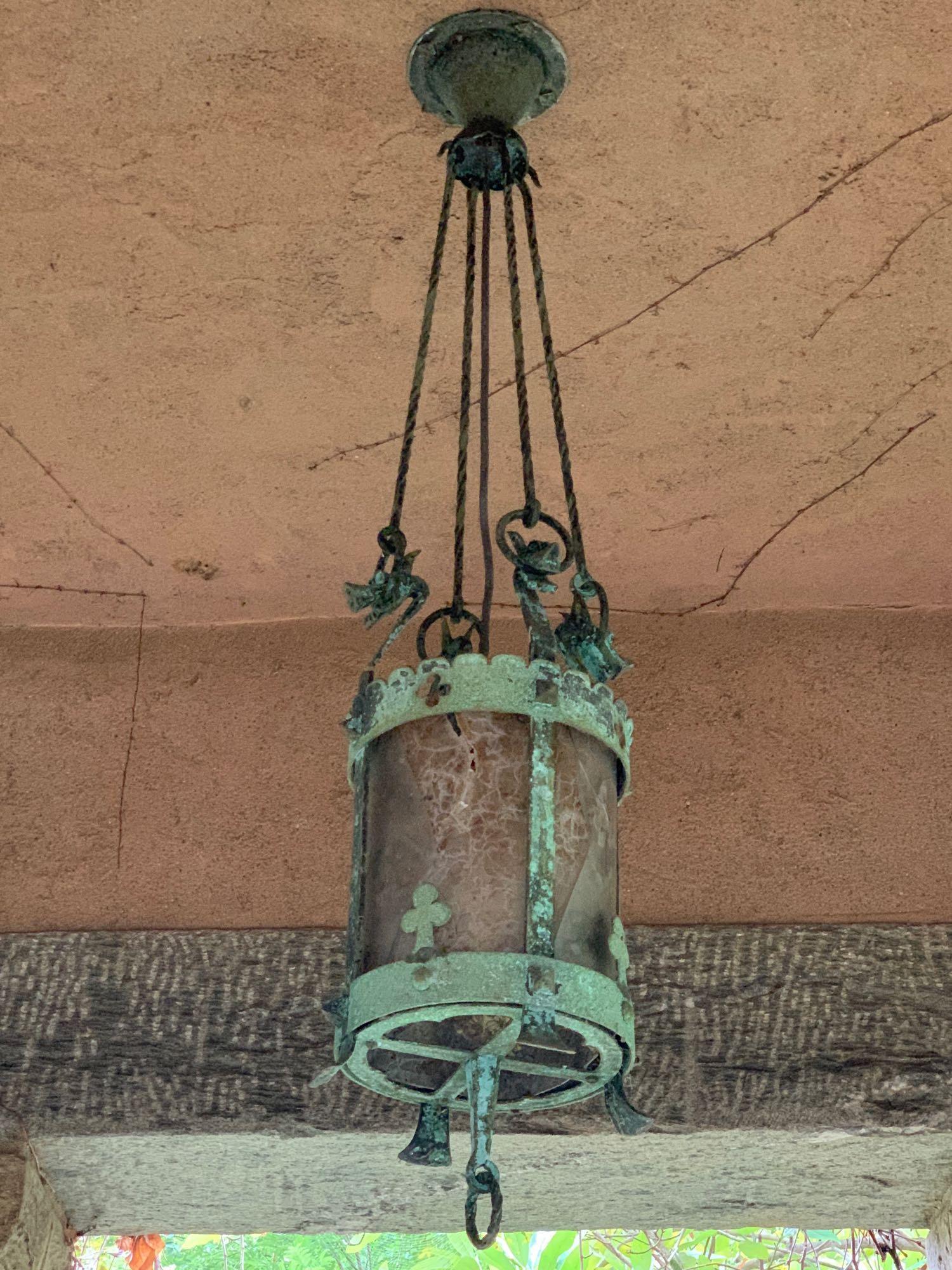 Arts & Crafts Hanging Lantern: A mica shade hanging lantern with a cylindrical frame with clover design, crested by four stylized dragons which hold four twisted supports that hook into ceiling cap. In the style of Samuel Yellin or