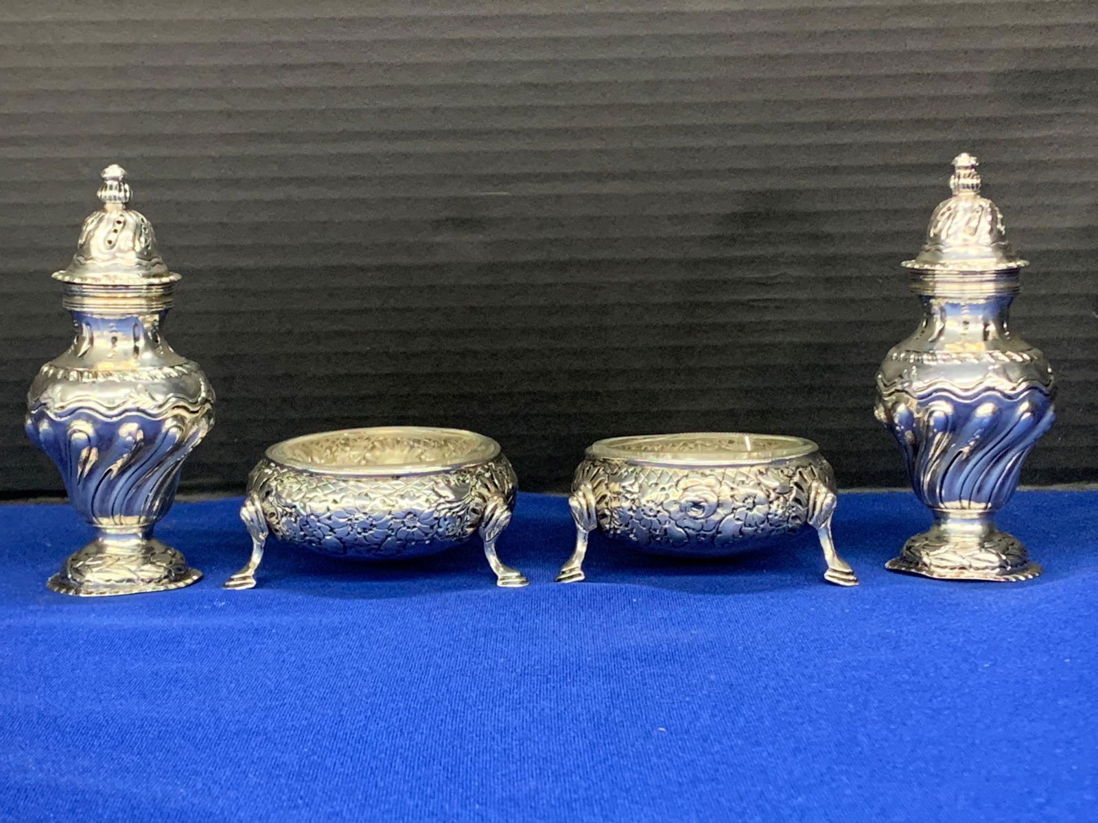 Four English Silver Early Victorian Salts: A grouping of two pairs of English silver salts to include a William Hutton & Sons salt and pepper shakers, and a pair of circa 1845 footed salt cellars with glass inserts hallmarked IE. Shakers: 4 in