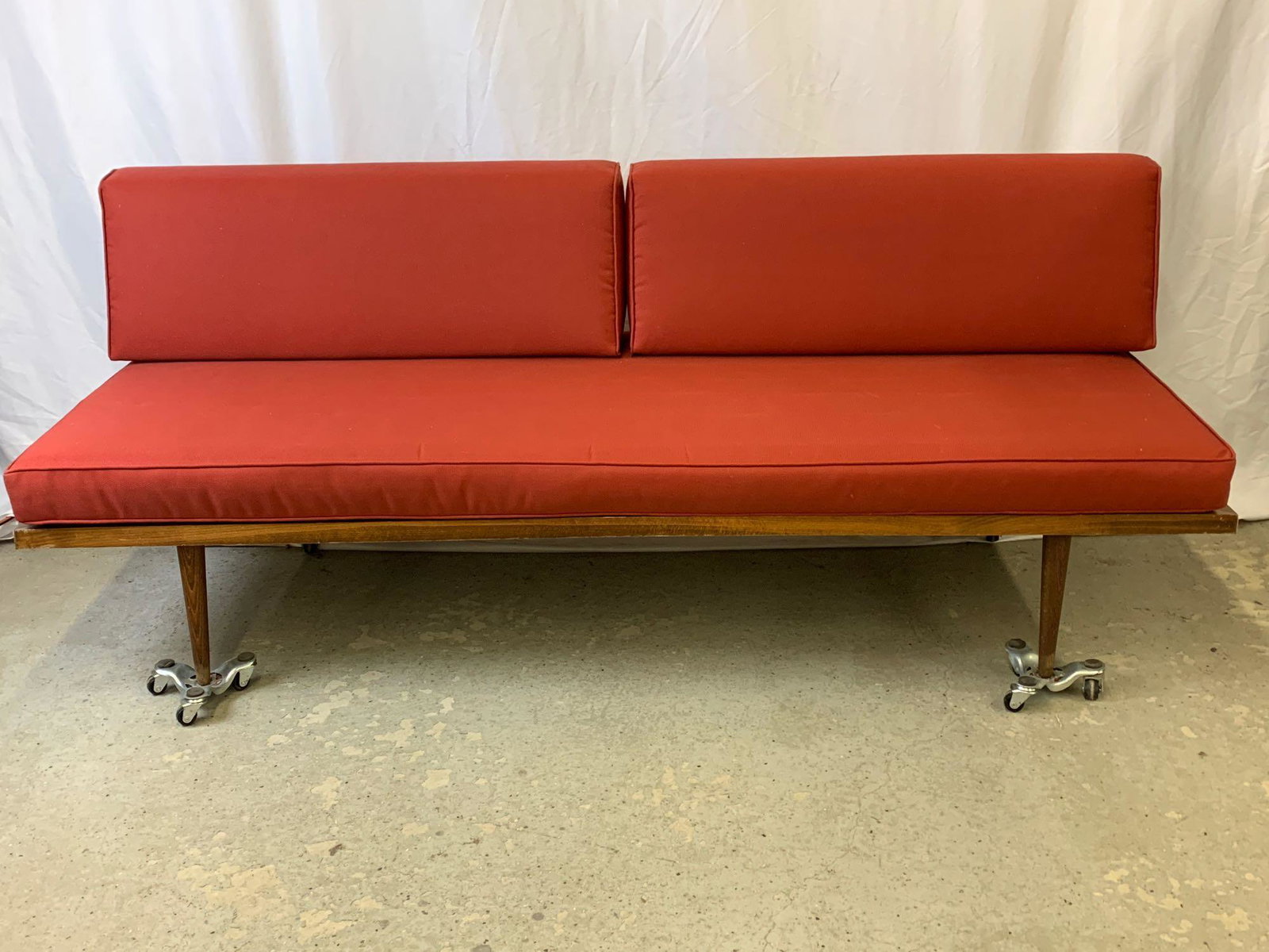 American Modern Daybed: An American midcentury modern daybed on tapering legs, recently upholstered in red. 29 in tall x 73 in wide x 30 in deep.
