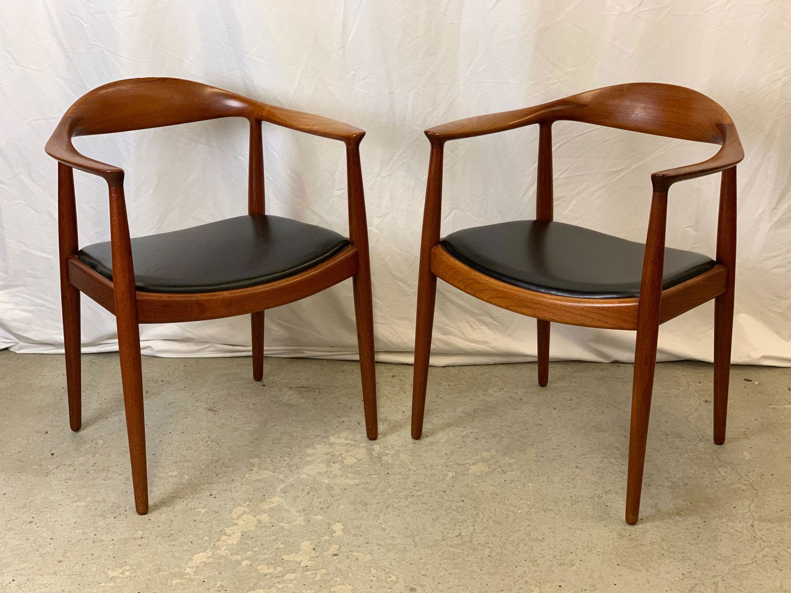 Pair of Hans Wegner/Johannes Hansen The Chairs: A pair of Hans Wegner for Johannes Hansen round chairs ("The Chair"), each with sculpted teak frames and branded marks. Each is 30 in tall x 24-3/4 in wide x 18 in deep.