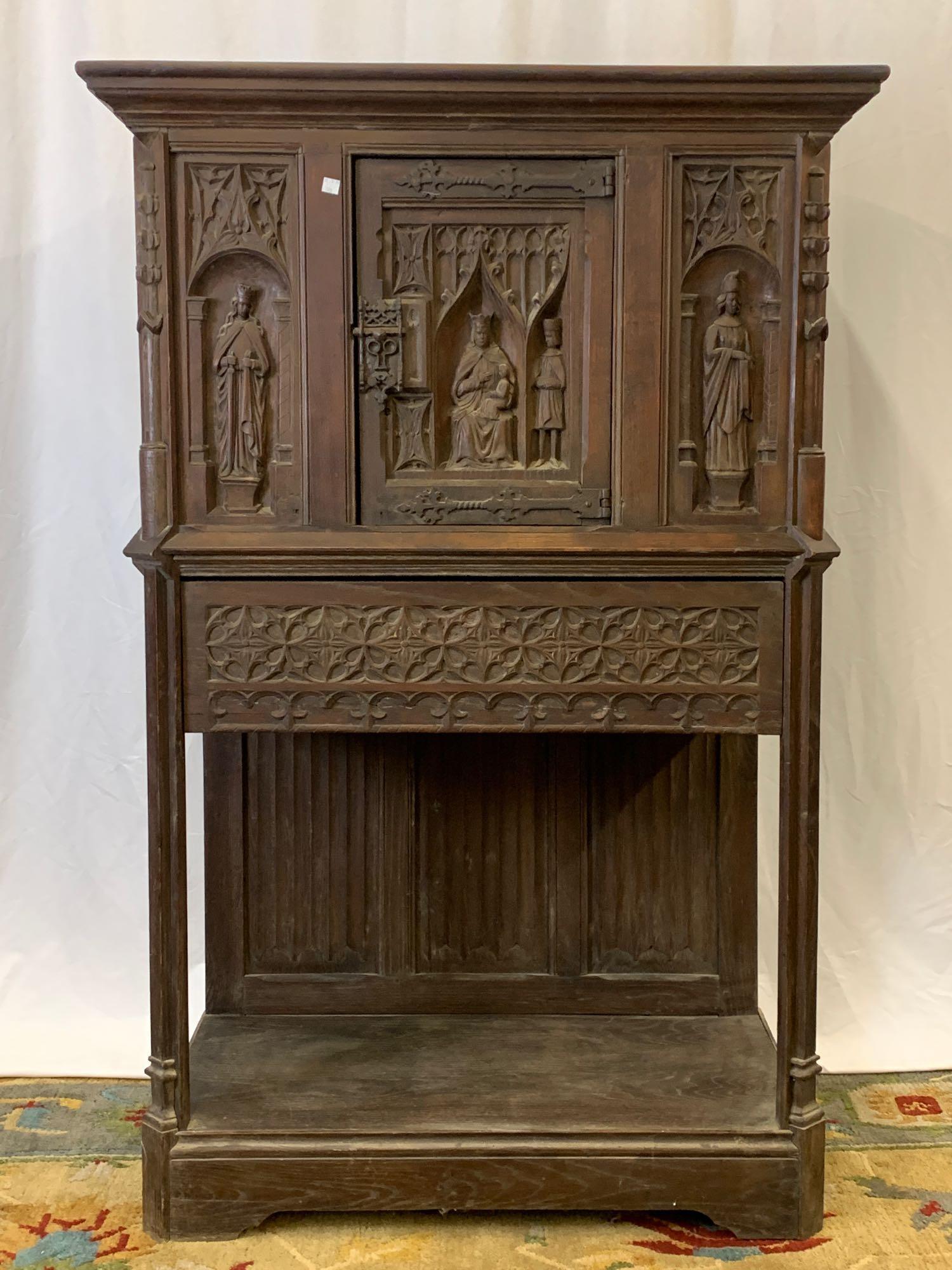 Continental Gothic Revival Wine Cabinet: A 19th Century Continental gothic wine cabinet having figural carved panels. 57-3/4in tall x 38in wide x 20in deep.