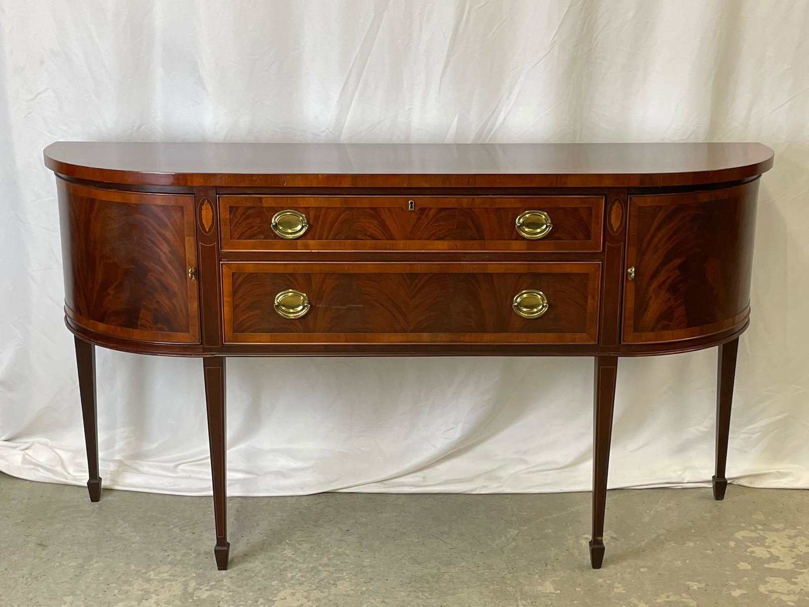 Heckman Federal-style Mahogany Sideboard: A Heckman Federal-style mahogany sideboard having a banded top over a case with two drawers and two cabinets, banded and with shell inlay, raised on four tapering legs ending in spade feet. With key. 