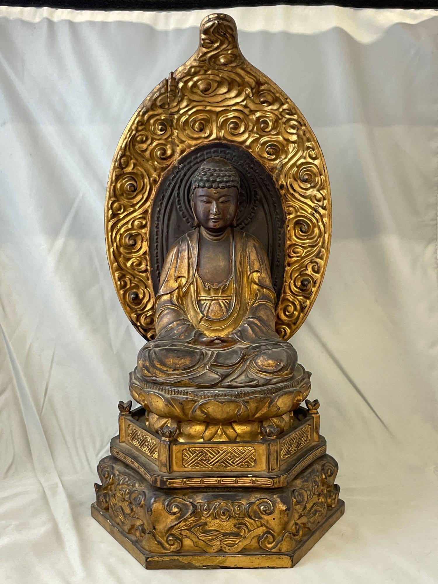 19th Century Carved and Giltwood Buddha: A 19th Century carved and giltwood Buddha temple figure raised on a lotus base with pedestal. Calligraphy marked on base. 17-1/4in tall x 9-1/4in wide x 8-3/4in deep.