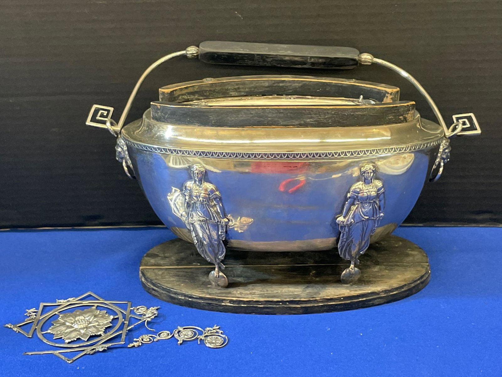 Hallmarked Figural Silver Container: A silver service container having a wood-mounted pierced hinged lid top over an ovoid base having lion mask ring handles and figural supports. Hallmarked with a "GB" in a diamond and a "GP" under a cr