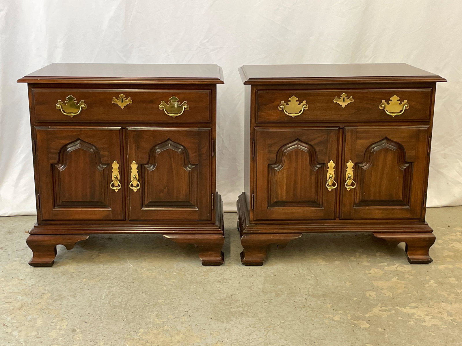 Pair of Harden Mahogany Chippendale-style Nightstands: A pair of Harden mahogany Chippendale-style nightstands with single drawers and paneled doors, on bracket feet. 26in tall x 26in wide x 16in deep.