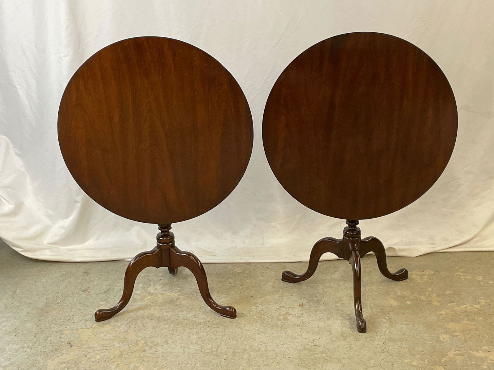 Pair of Hitchcock Tilt-Top Tea Tables: A pair of Hitchcock mahogany tilt-top tea tables with circular tops, turned shafts, and tripod bases. Each: 25-1/2in tall x 26in diameter.