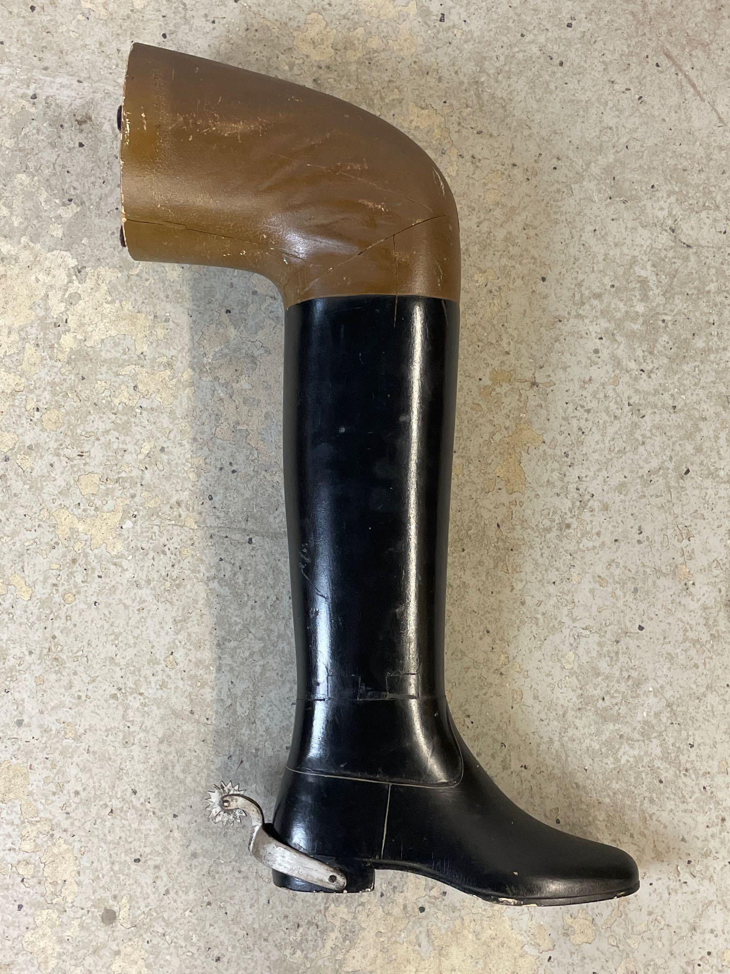 Wall-mounted Boot-form Trade Sign: A wall-mounted carved and painted wooden trade sign in the form of a boot with metal stirrup and leg. 27in tall x 19in wide.