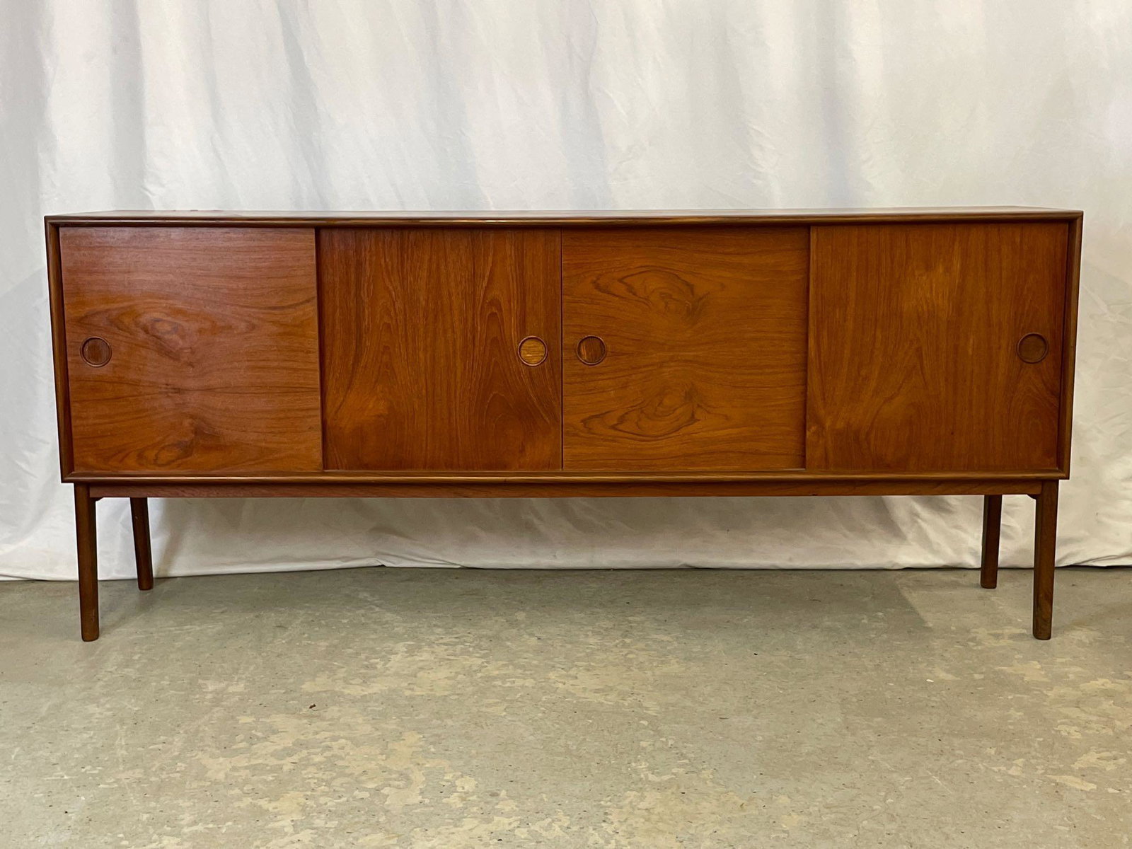 Danish Modern Teak Credenza: A Danish modern teak credenza or sideboard having four sliding doors and a drawered and shelved interior, raised on tapering legs. Unmarked. 31in tall x 72in wide x 17in deep.