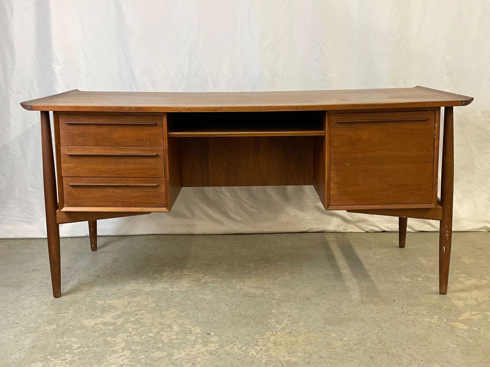 Arne Vodder for HP Hensen Danish Modern Teak Desk: An Arne Vodder for HP Hensen Danish modern teak desk having a sculpted rectangular top, a floating case fitted with drawers, and finished back with open bookcase compartment and cabinet, raised on tap