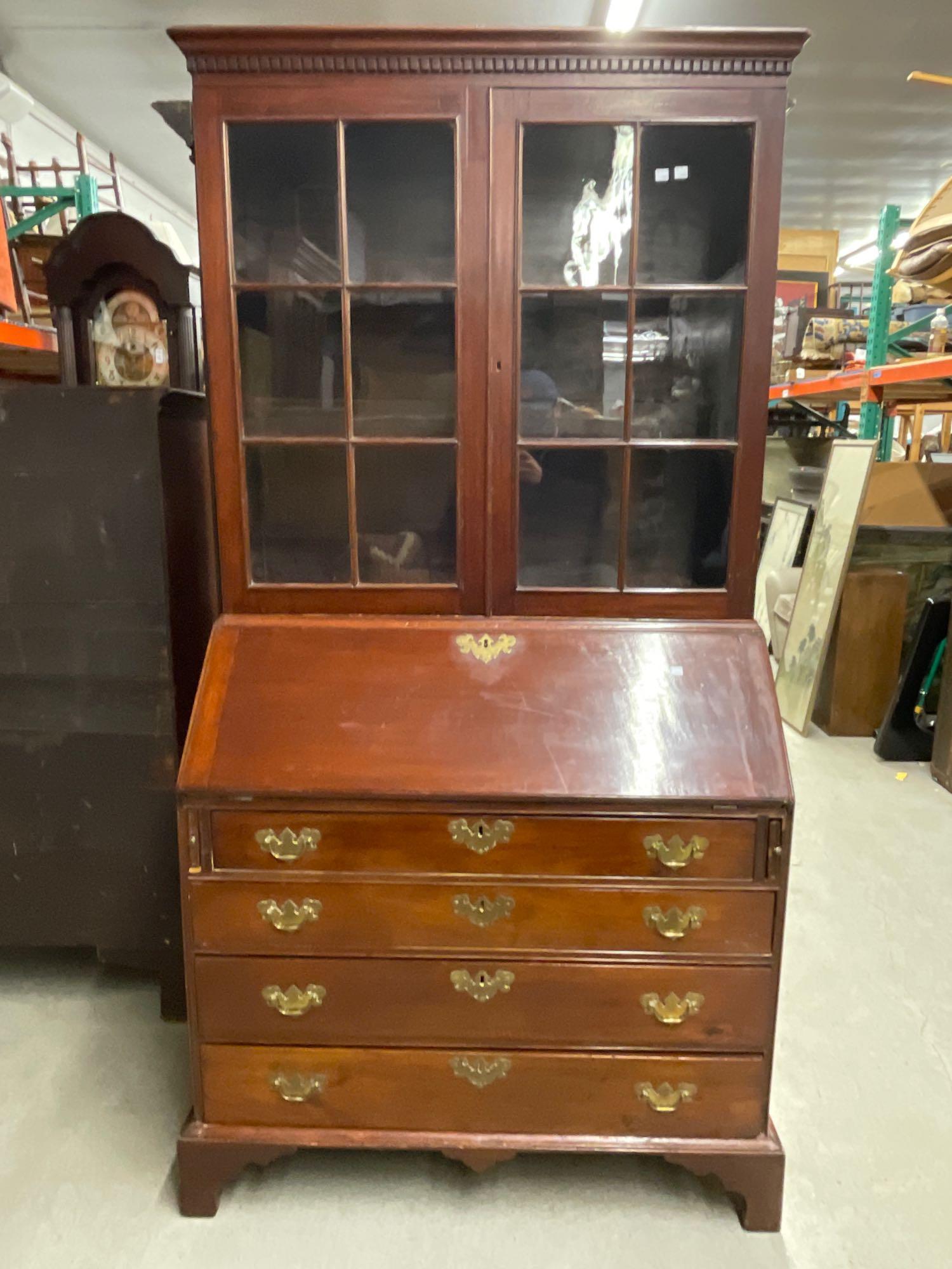 Chippendale Mahogany Secretary Desk: A Chippendale mahogany secretary desk having a dental carved glass paned bookcase top over a slant-lid desk case with four graduated drawers on straight bracket feet. 77-1/4in tall x 38-1/2in wide x 1