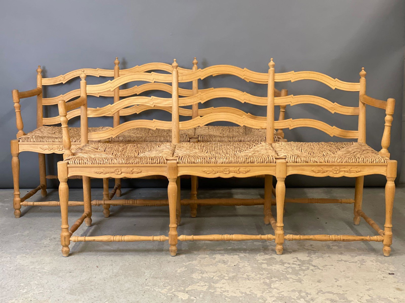 Pair of Country French Benches: A pair of country French benches or settees with carved natural wood frames and rush seats. Each: 34in tall x 58-1/2in wide x 19in deep.