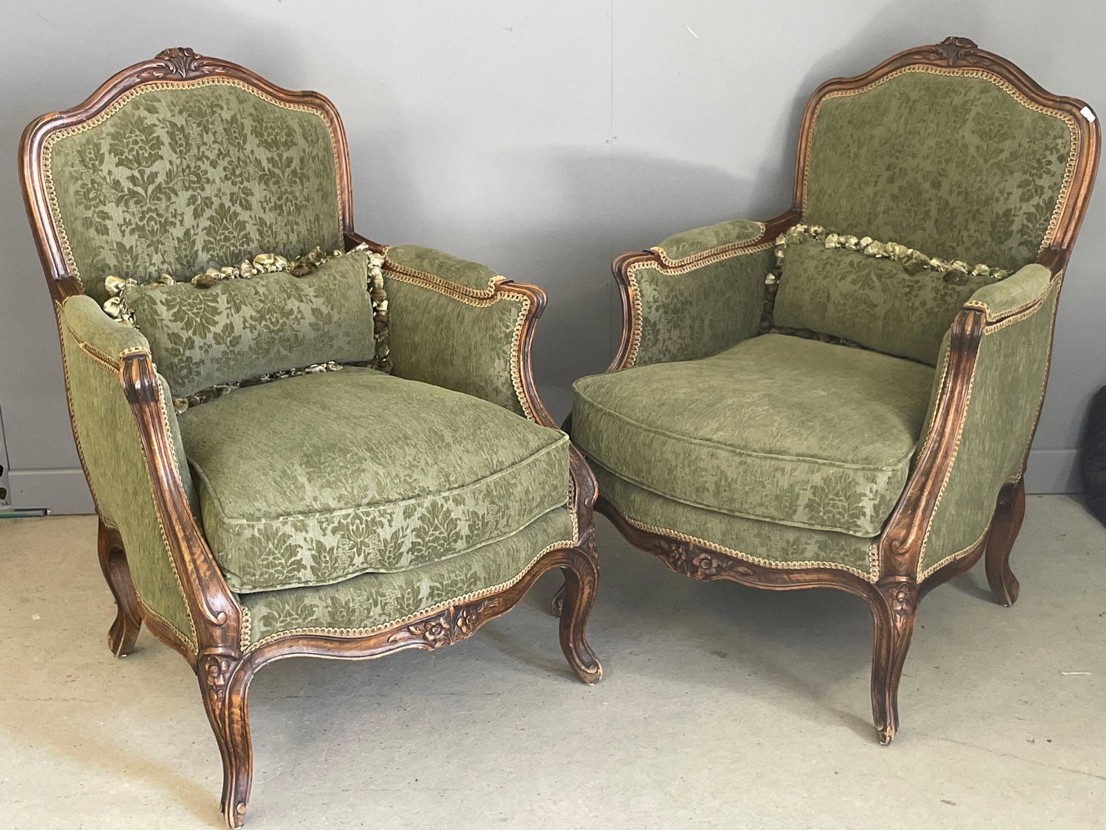 Pair of Louis XV-style Bergeres: A pair of French Louis XV-carved bergÃ¨re armchairs with green upholstery. Each: 38in tall x 27-1/2in wide x 24in deep.