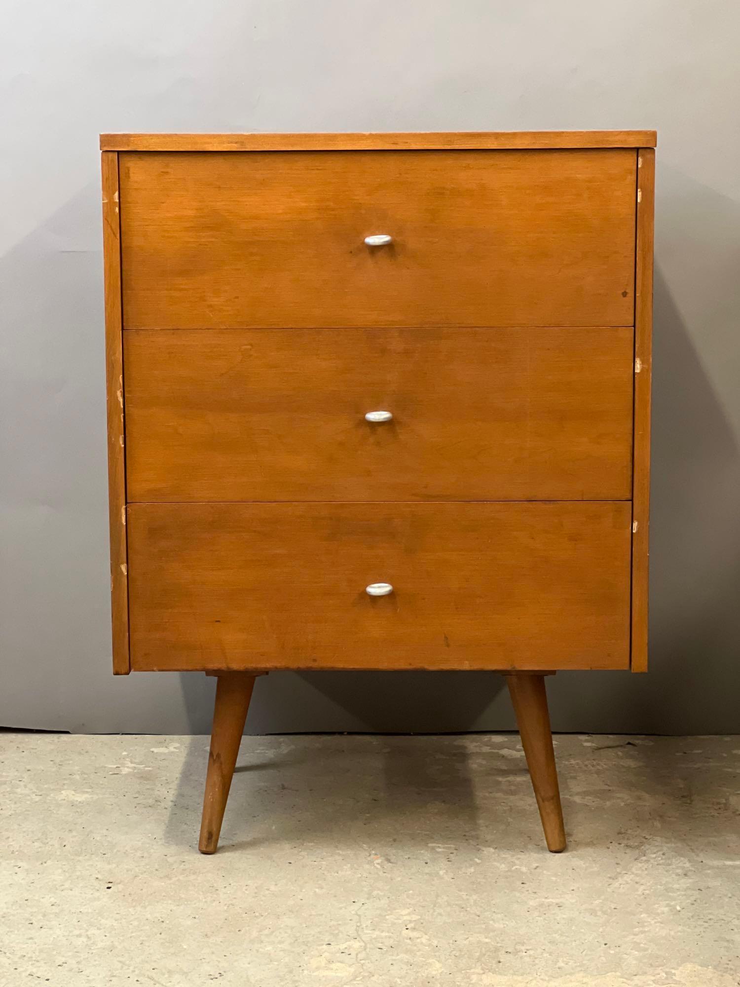 Paul McCobb Planner Group Three-drawer Nightstand: A Paul McCobb Planner Group three-drawer nightstand with ring pulls and splayed tapering legs. Unmarked. 33-1/4 in tall x 24 in wide x 18-1/2 in deep.