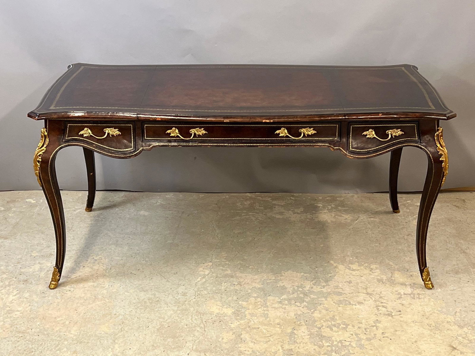 Maitland Smith Leather Wrapped Bureau Plat: A Maitland Smith Louis XV-style leather-wrapped bureau plat or writing desk with three drawers and ormolu mounts. 29-1/2in tall x 63in wide x 31-1/2in deep.