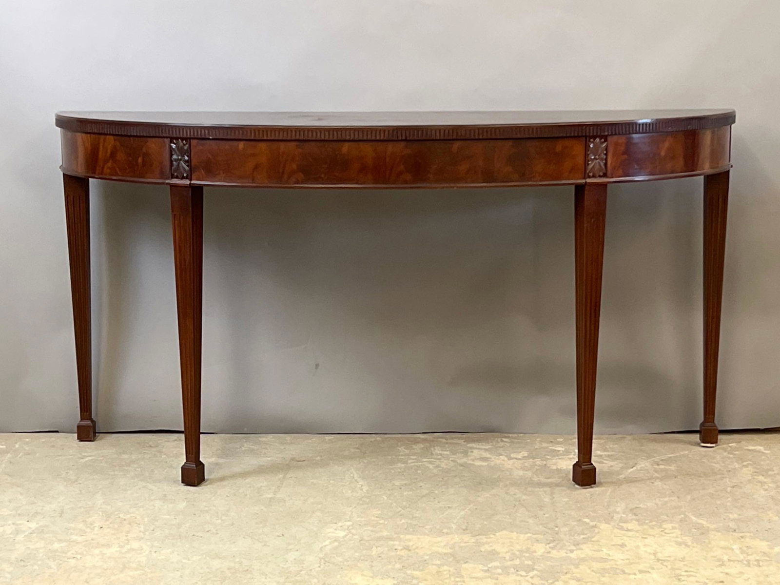Baker Federal-style Console Table: A Baker mahogany Federal-style one-drawer demilune console table. 34-1/2in tall x 68in wide x 22in deep.