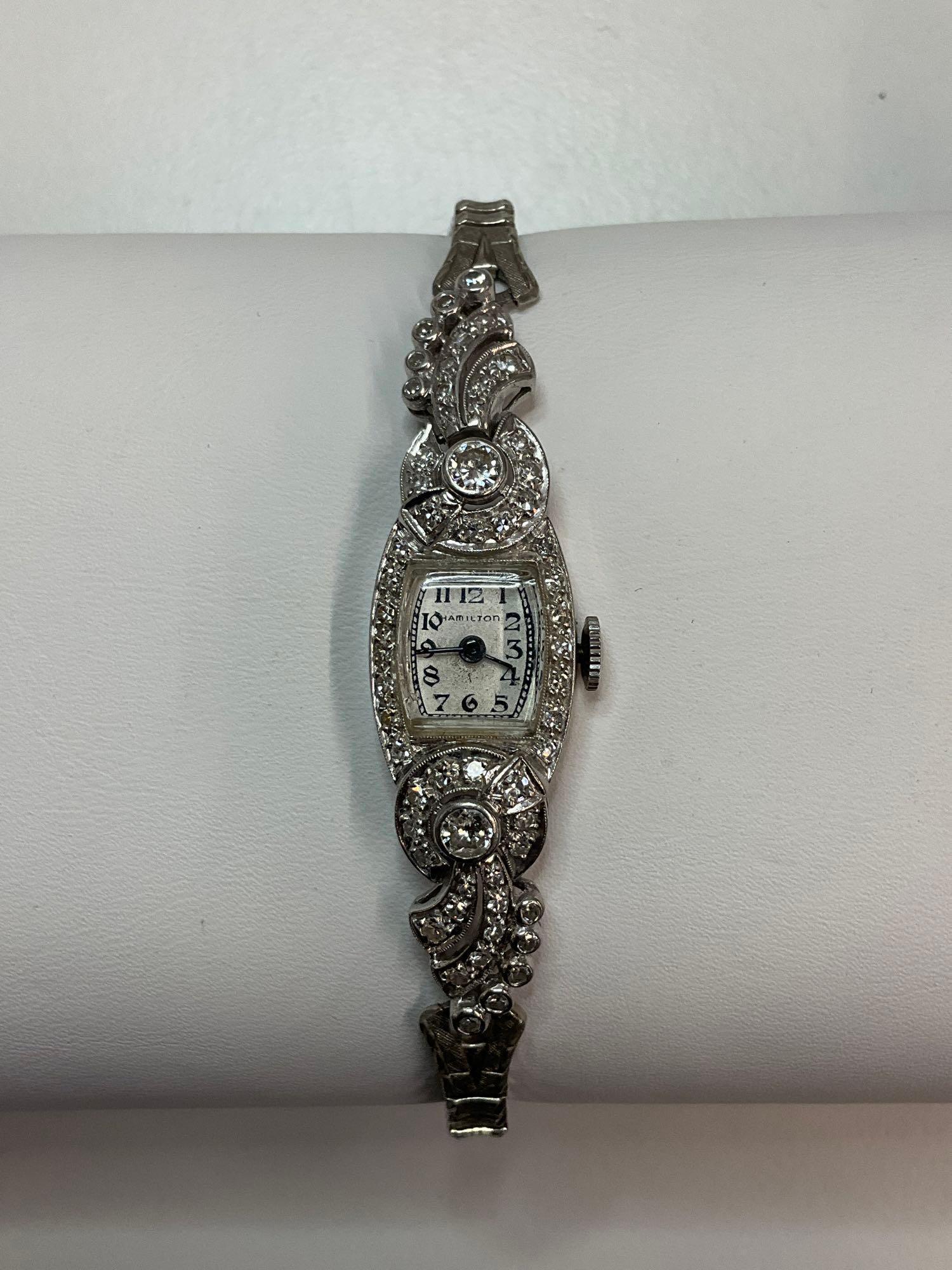 Ladies Vintage Hamilton Watch with Diamonds: A ladies vintage Hamilton wristwatch with platinum diamond case. 22 jewels. Largest diamonds are approx. 20 points each. Case back is marked "10% Irid. Plat." Case is approx. 2-1/4in long x 5/8in wide