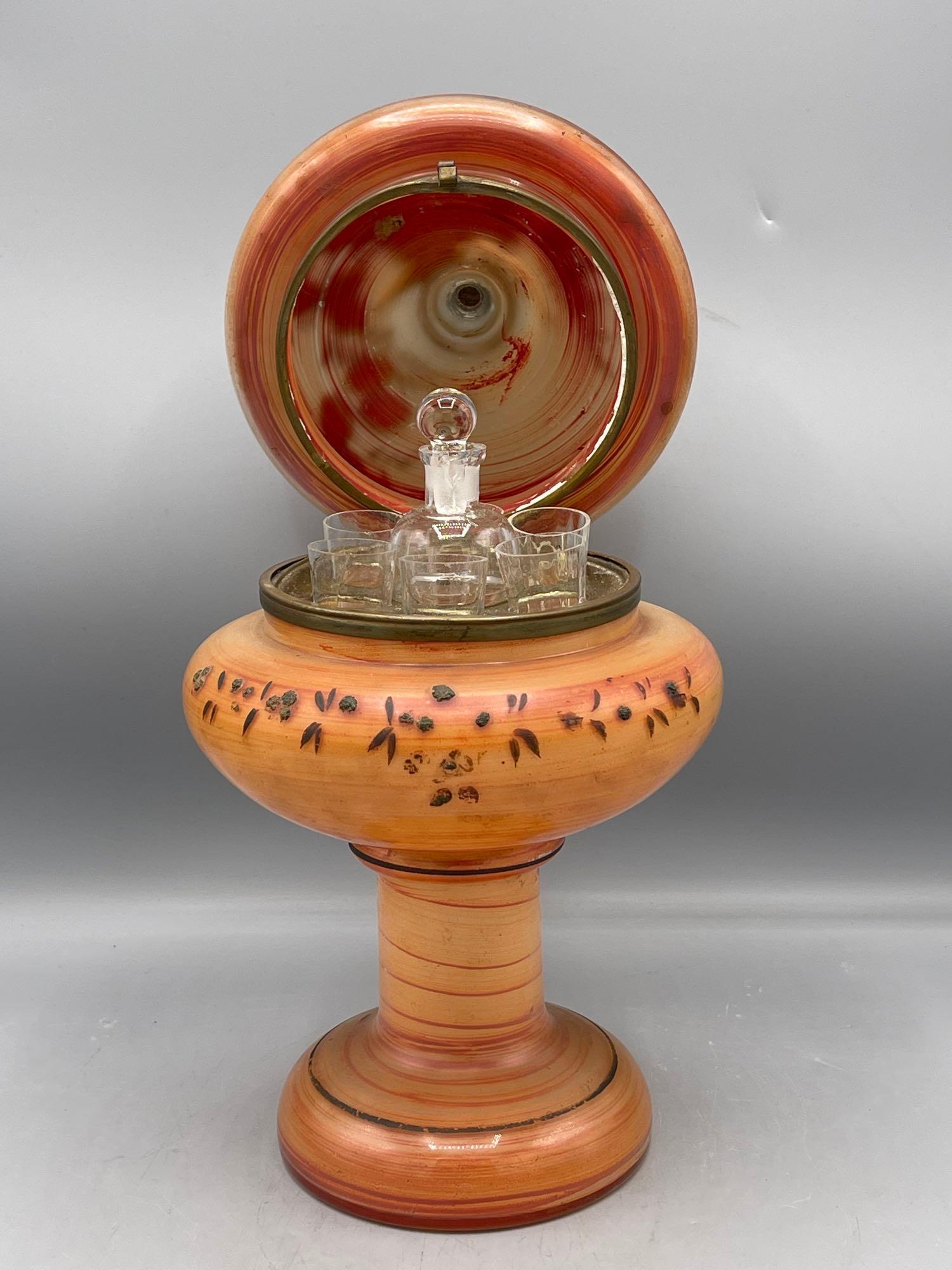 Glass Cordial Set in Glass Caddy: A hand-painted glass lidded vessel with interior cordial set with gold relief detail, marked illegibly on base. 12-1/2in tall x 6-1/2in wide.