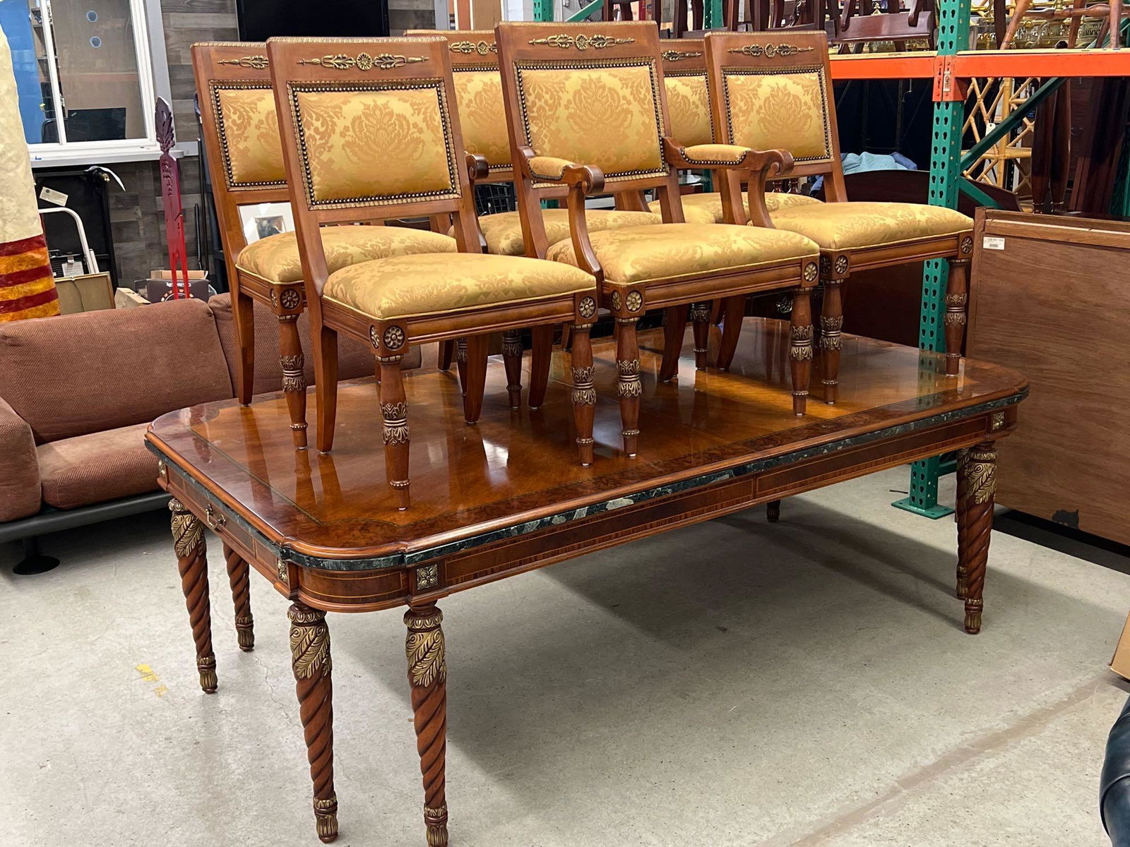 Henredon Empire-style Dining Table and Chairs: A Henredon French Empire-style extension dining table with a banded and inlaid top with marble trim, drawers on either end, and raised on eight spiral turned legs. With two leaves and six matching cha