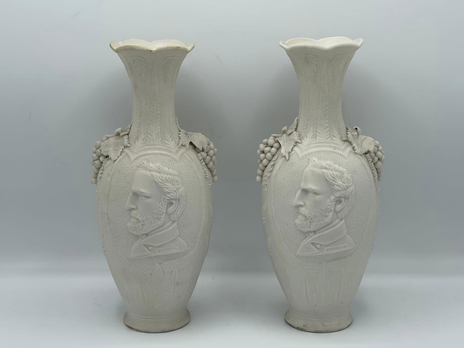 Pair Ulysses S. Grant Parian Portrait Vases: A pair of Civil War-era Parian-wear vases with Ulysses S. Grant relief portrait and grape decoration. 10in tall x 4in wide.