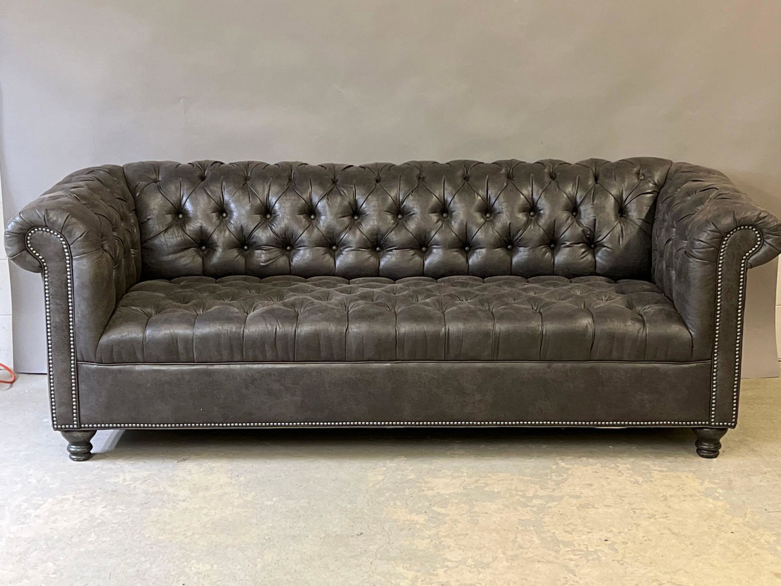 Decorator Chesterfield Sofa: A contemporary decorator grey chesterfield sofa with rolled arms and tacked trim. 30in tall x 86in wide x 36in deep. | Local and NYC curbside delivery details and international third-party shipper rec