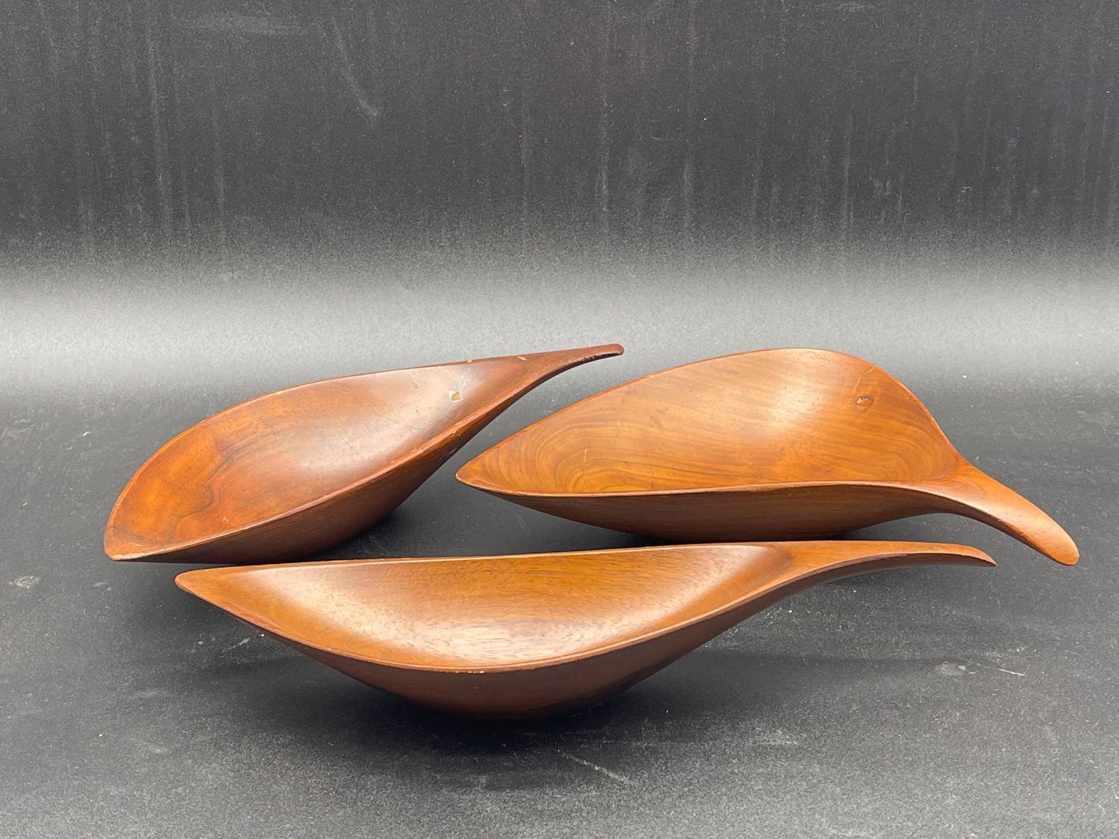 Three Emil Milan Walnut Bowls: Three Emil Milan walnut carved amoeba bowls. Signed on base "Emilan Walnut". Largest: 2in long x 4in wide. | Local and NYC curbside delivery details and international third-party shipper recommendatio