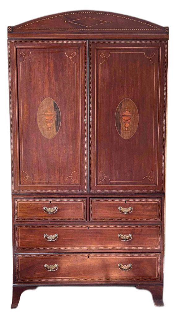 George III Inlaid Mahogany Linen Press: A George III mahogany linen press in three parts, with an urn-inlaid upper case over drawers, raised on French flared feet. 92in tall x 48-1/2in wide x 24in deep. Pendulum and two weights are present.