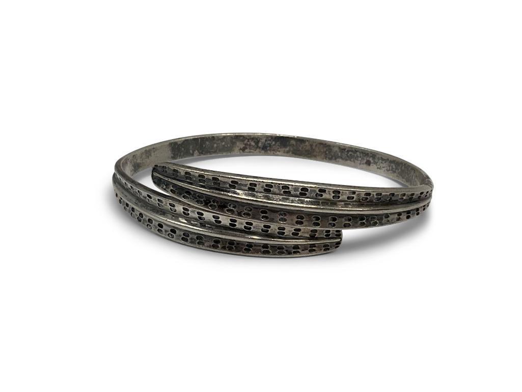David Andersen Sterling Bangle Bracelet: An oval David Andersen sterling bangle bracelet with stamped design on the front half of the bangle. Marked "D-A 925S Norway Sterling" with scale hallmark. Approx. 3/4in wide at widest point, tapering
