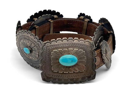 Native American Concho Belt: A Native American sterling silver Concho belt with 12 alternating conchos, the larger with mounted turquoise cabochons. Buckle has a stamped signature verso and is marked Sterling. Belt is Levi's bran
