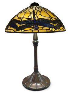 Tiffany Studios Dragonfly Table Lamp: A Tiffany Studios leaded glass and bronze dragonfly lamp with a cream-colored slag glass shade featuring seven reticulated bronze overlay dragonflies with blue glass inserts and a pierced bronze heat