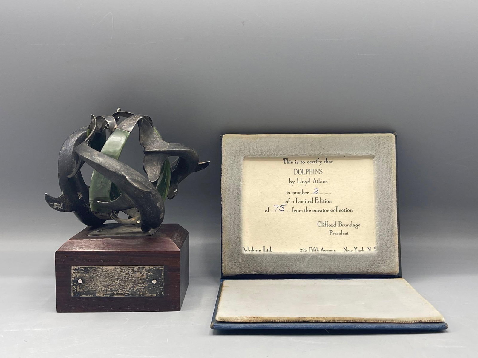 Lloyd Atkins Bronze Dolphins: Lloyd Atkins (American, b. 1922). A bronze sculpture of leaping dolphins with green stone accents. Includes COA from Delphine Ltd., noting this is number 2 of a limited edition of 75.Sculpture: 5-1/2i