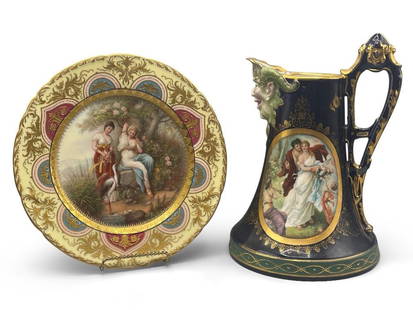 Royal Vienna Plate and Pitcher: A Royal Vienna gilt-decorated plate with central nymphs and stork, marked Austria with beehive; and a cobalt blue porcelain pitcher with a horned face spout with portrait center, marked Royal Vienna.