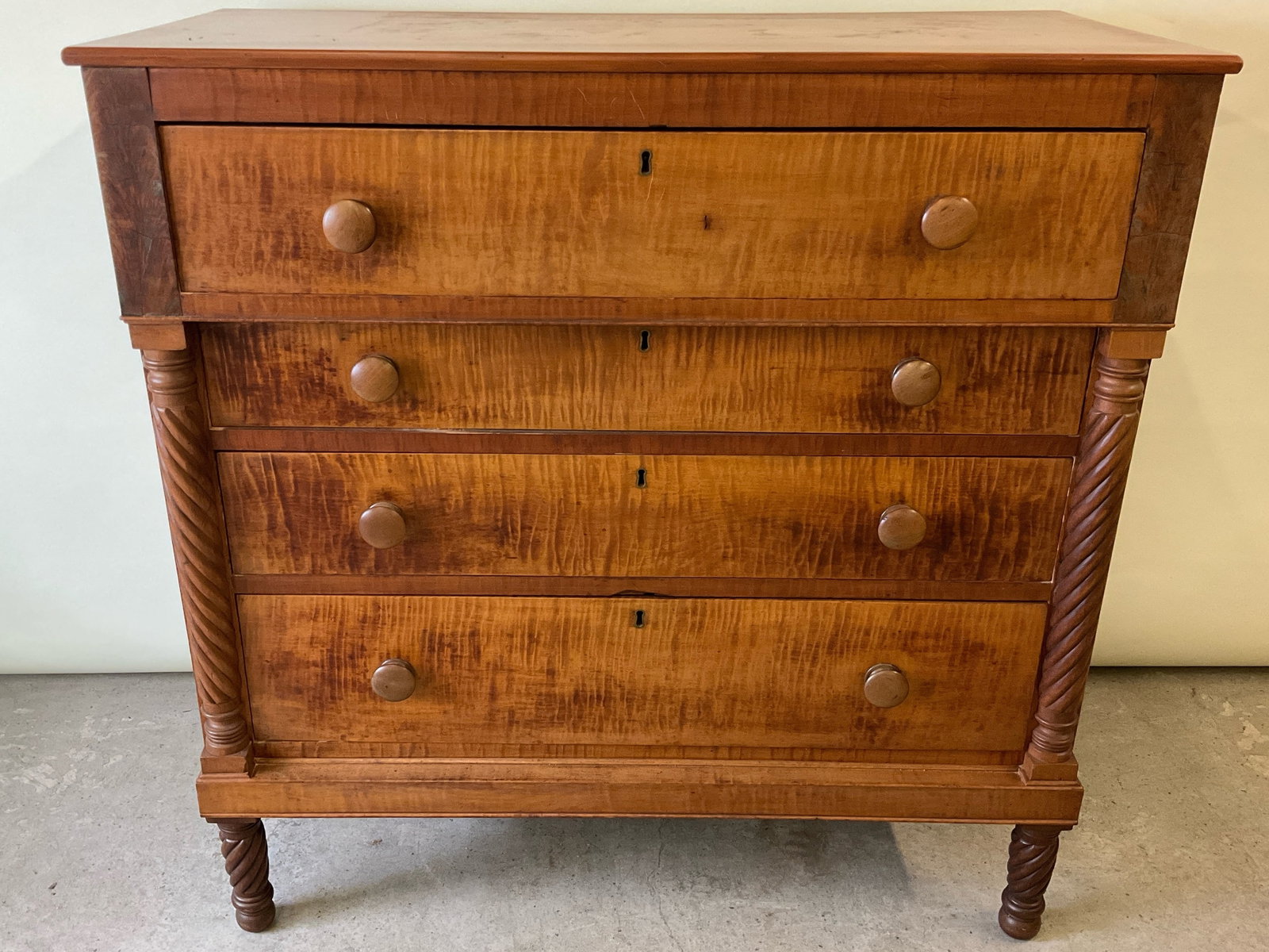 Tiger Maple Chest of Drawers: A tiger maple chest of drawers with an overhanging top drawer over three graduated drawers, flanked by carved twisted columns and supported on turned legs. 43-1/2in tall x 43in wide x 20in deep. | Phi