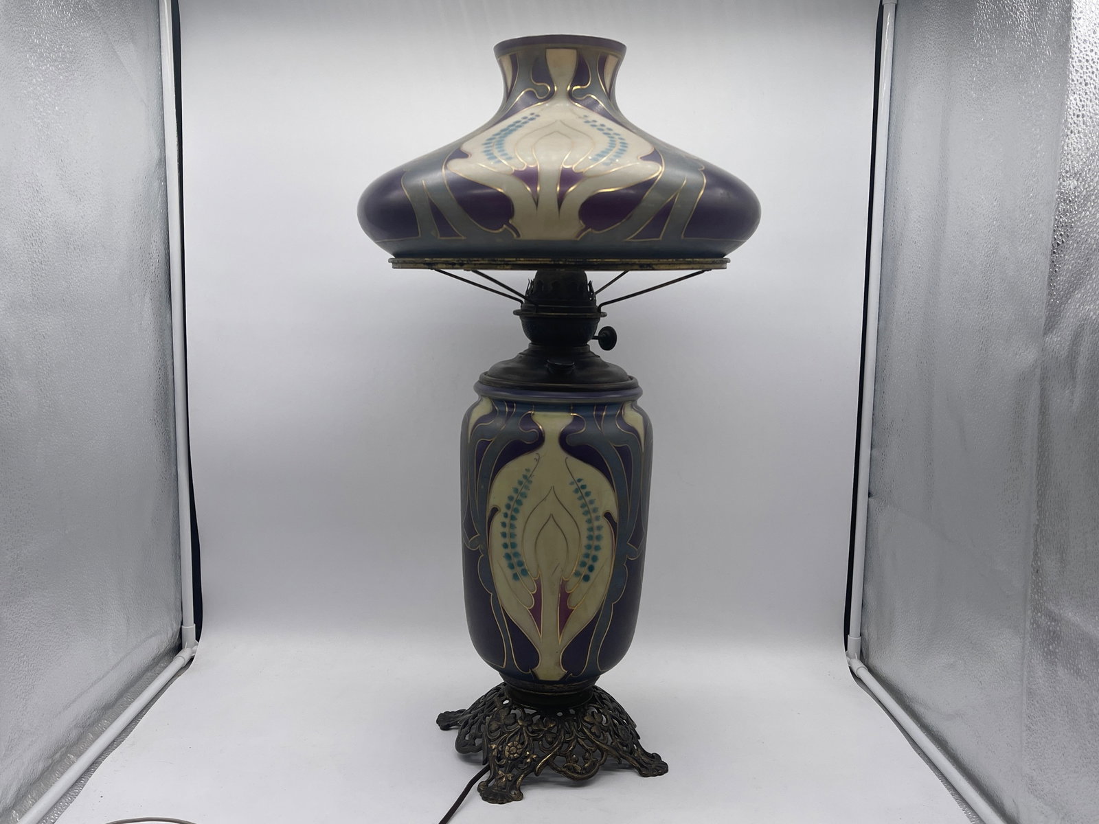 Art Nouveau Decorated Glass Lamp: An Art Nouveau purple-hued and gilt-decorated glass lamp resting on brass filigree base. Unsigned. 27 in tall. | Philadelphia Metro area delivery, NYC curbside delivery, and international third-party 