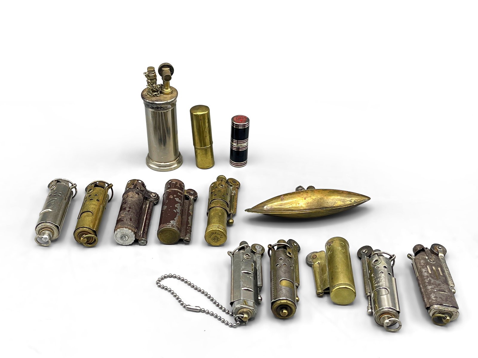 14 Trench Art Lighters: A grouping of 14 Trench Art metal lighters to include Dunhill, Surelite, Bowers of Kalamazoo, New Haven Connecticut, and a Remington Rand lighter. Largest: 3-1/2in tall. | Philadelphia Metro area deli
