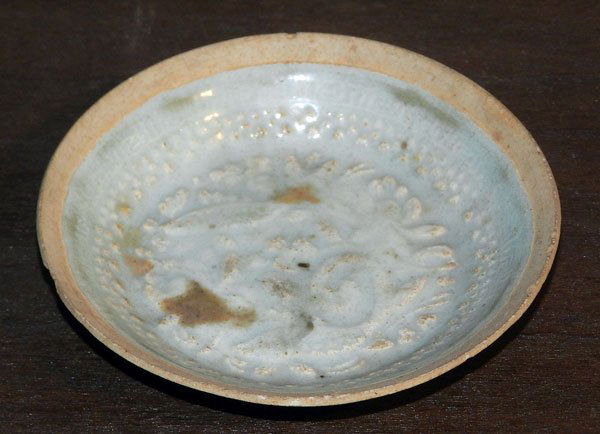 Small Chinese Porcelain Bowl: Small Chinese porcelain bowl with raised molded design of fish and plates. Pale celadon glaze, with unglazed rim. 1/2" tall; 4" diameter.