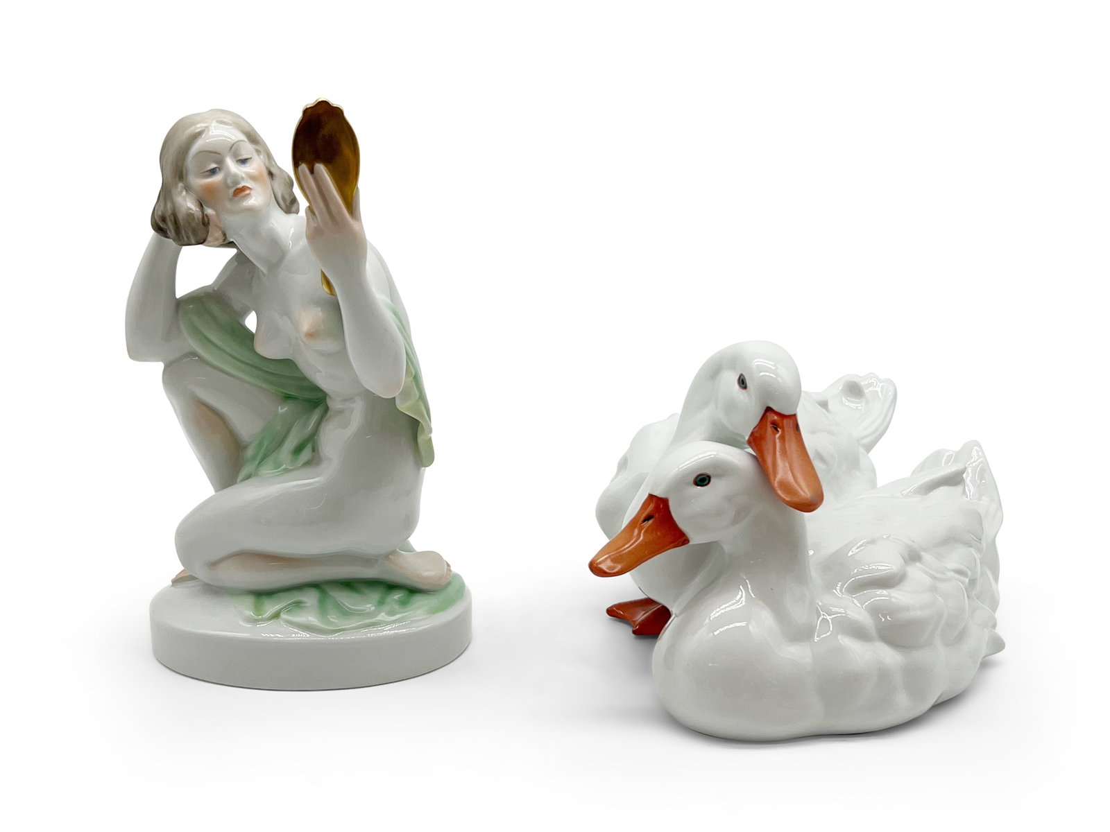 Two Herend Porcelain Figures: Two Herend porcelain figures to include a pair of intertwined ducks and a nude woman holding a mirror. Woman: 9-3/4in tall x 5-1/2in wide. | Philadelphia Metro area delivery, NYC curbside delivery, an