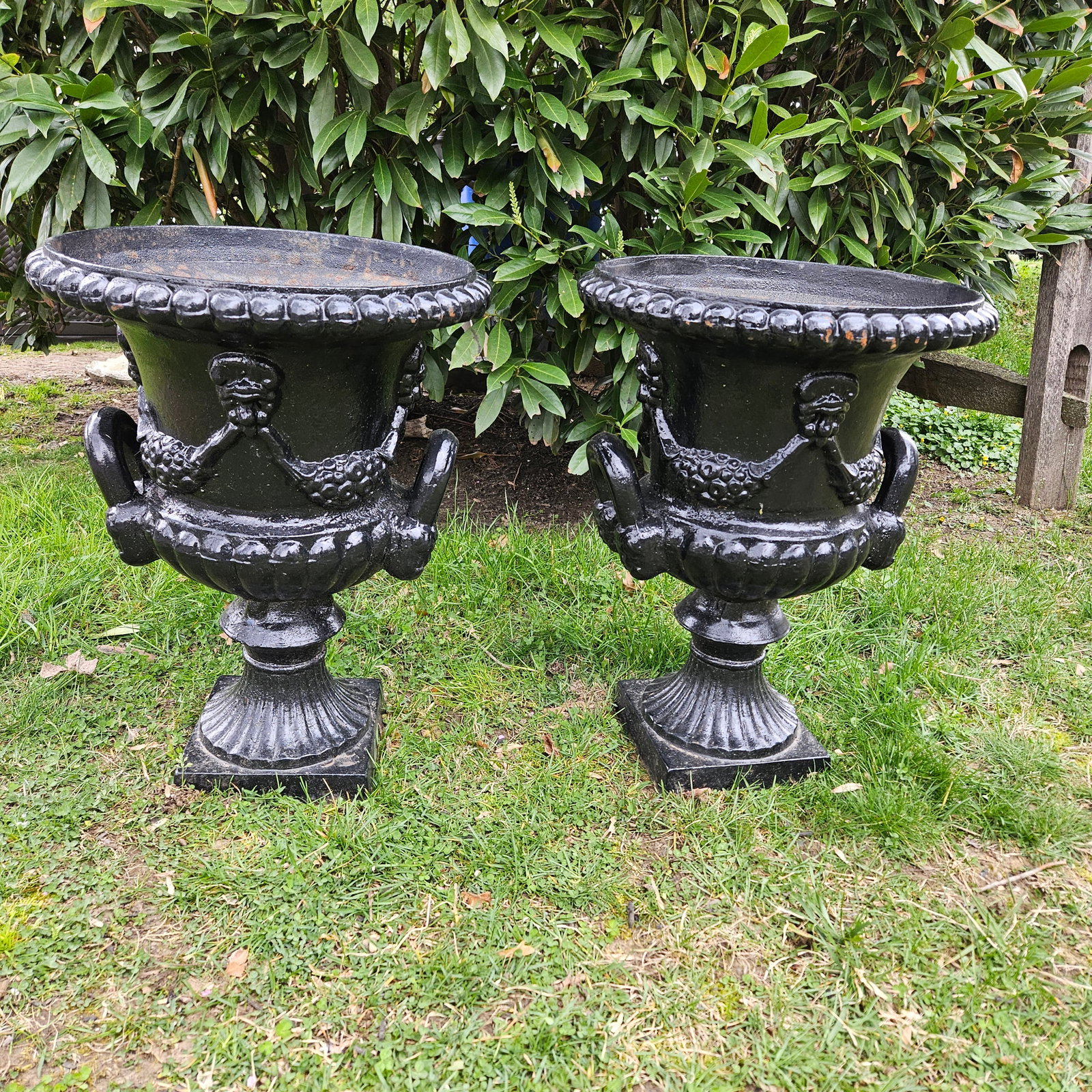 Pair of Cast Iron Garden Urns: A pair of cast iron garden urns with bellflower swag and handles. Approx. 24in tall x 17-1/2in wide. | Philadelphia Metro area delivery, NYC curbside delivery, and international third-party shipper in