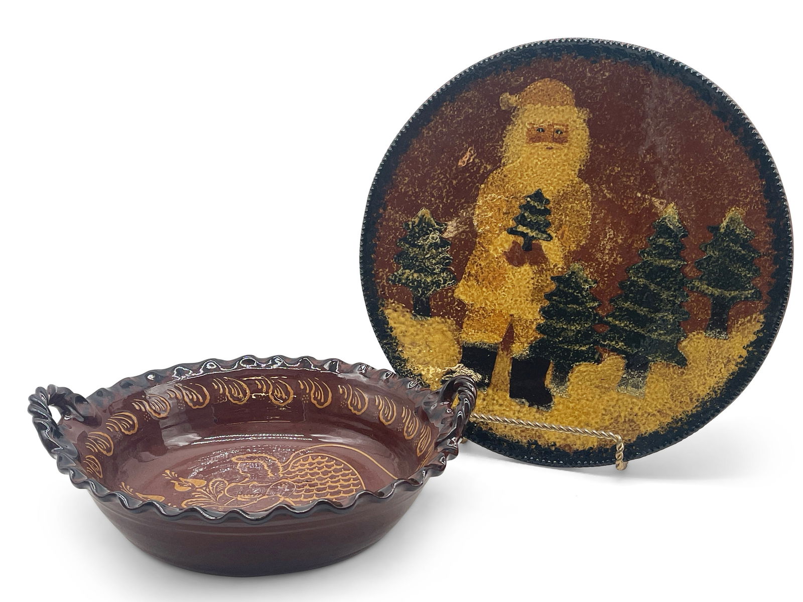 Two Pieces of Ned Foltz Redware Pottery: Two pieces of Ned Foltz Pennsylvania redware pottery to include a large plate with mottled Santa motif impressed with Foltz pottery marking, and a handled bowl with slip-decorated angel motif, signed