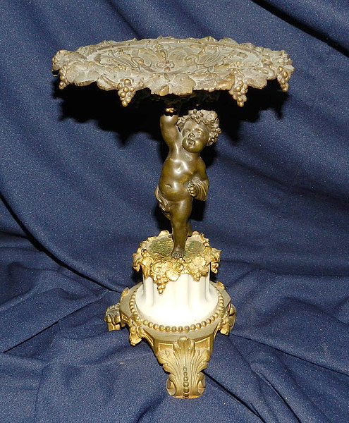 Bronze Plateau: Gilded-bronze plateau with black finish, with putti support on an alabaster column. Unmarked. 11" tall, 7-1/2" diameter.